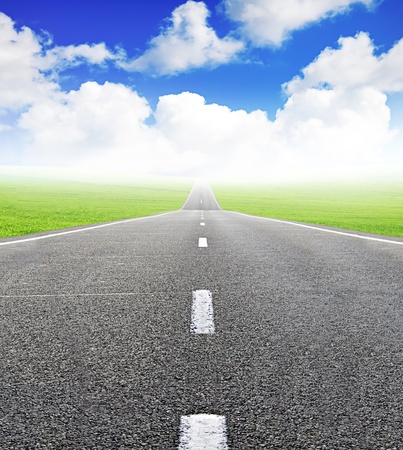 green field and road over blue sky - travel and tranportation conceptの写真素材