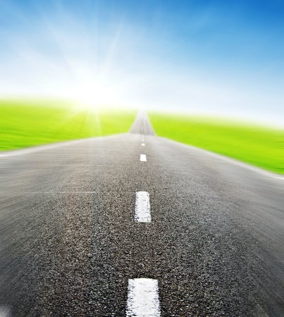 green field and road over blue sky in motion- travel and tranportation conceptの写真素材