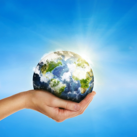 female hand holding globe over blue sky - environment protection and travel concept -Elements of this image furnished by NASAの写真素材