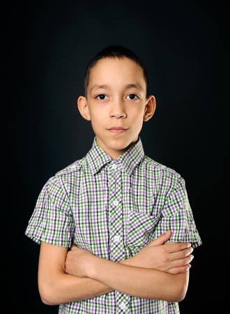 portrait of calm young boy looking at camera over black backgroundの写真素材