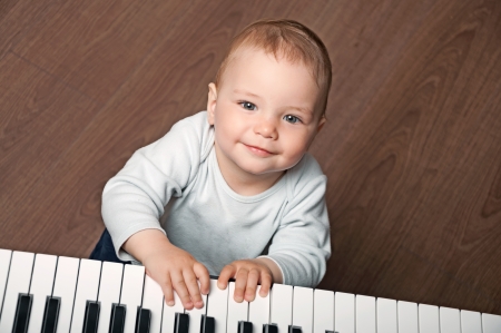 portrait of little baby child  play music on black and white piano keyboardの写真素材