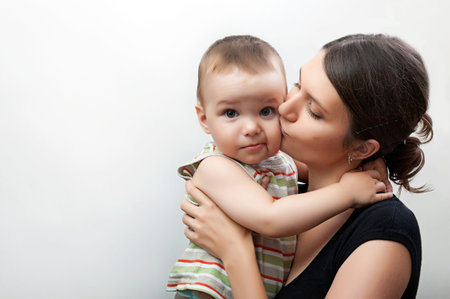 portrait of happy young mother and toddler on white and grey background