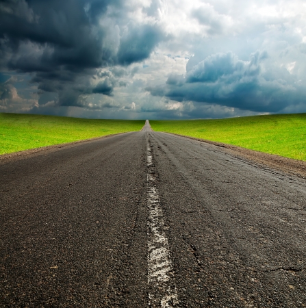 old broken asphault road in green field over blue cloudy skyの写真素材
