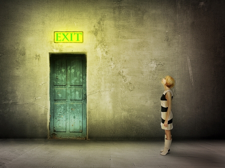 young woman in black and white dress stand in front of blue door in dark grungy room watch on glowing exit sign - find the way outの写真素材