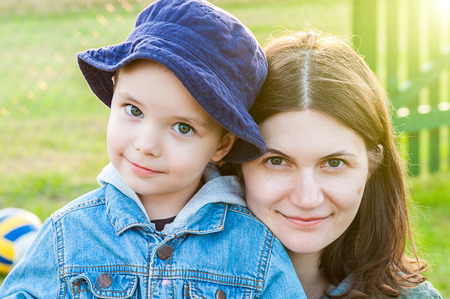 portrait of young woman and boy mother and son family in summer sunshine over greenの写真素材