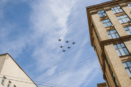 MOSCOW-MAY 9, 2015: Victory parade dedicated to the 70th anniversary of the Soviet victory over Germany. Demonstration aircraft flying over the rooftops of the city and the heads of the people, the view of a city block.のeditorial素材