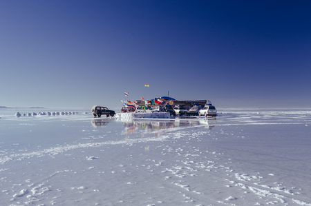 BOLIVIA, UYUNI-APRIL, 2011:Vehicles on which the tourists travel by Salar de Uyuni. Salt Hotel and flags of the states.のeditorial素材