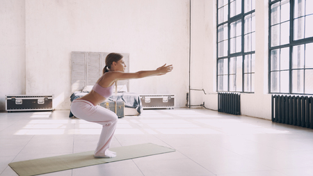 Yoga at home. A girl in pink sports clothes makes asanas at home.の写真素材