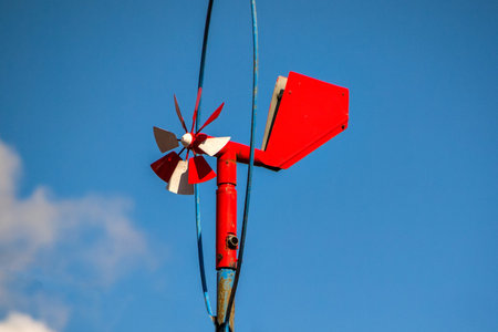 homemade red weather vane with a propeller against a blue sky .