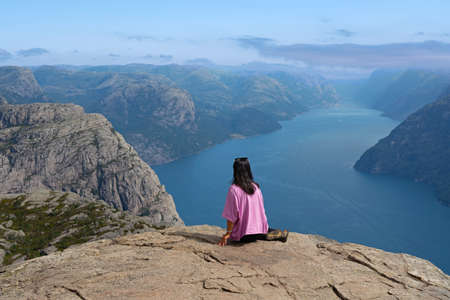 Woman sitting on the rock near Preikestolen, Norway, Lysefjord sea view.の写真素材