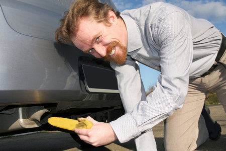Man putting banana into car exhaust pipeの写真素材