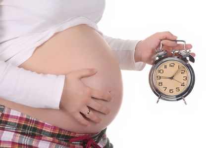 pregnant woman with alarm clock waiting on white backgroundの写真素材