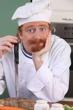 Young chef with a knife, thinking for prepare lunchの写真素材