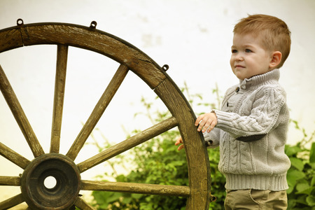 curious Baby boy with old wooden wheel の写真素材