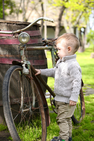 2 years old curious Baby boy walking around the old bikeの写真素材