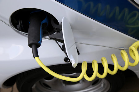 Electric car being charged at the station, close up of the power supply plugged