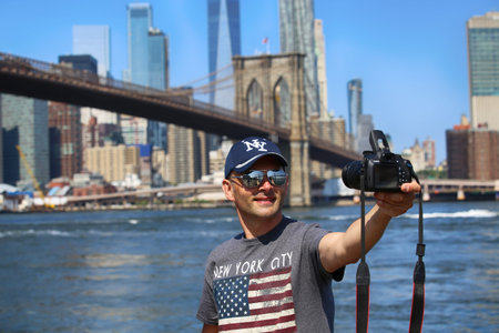 New York, USA â August 23, 2018: Tourist taking a selfie from the Empire Fulton Ferry Park, view scene of the Brooklyn bridge and Manhattan Skyline.のeditorial素材