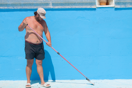 Painting a huge blue Swimming Pool. A maintenance worker poolの写真素材