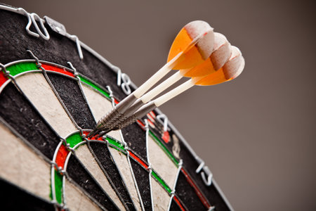 Three darts hitting perfect 180 score on dart board.