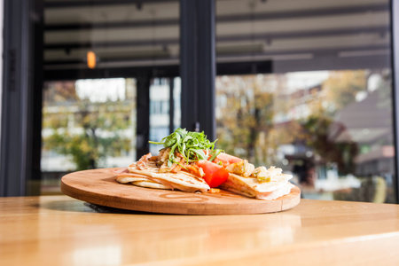 Sandwich with ham, tomato, cheese and golden French fries potatoes on a wooden plate.