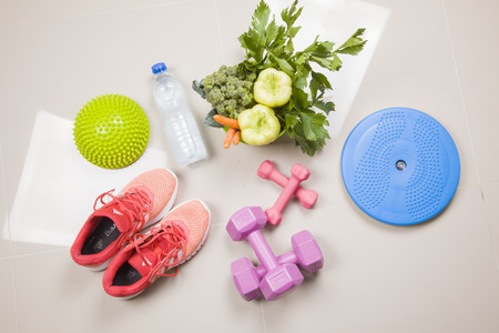 Sport shoes sneakers, water, measuring tape and apples on white background. Top view sport equipment. Healthy life and healthy food conceptの写真素材