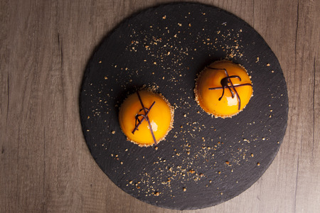 close-up of beautifully decorated delicious yellow pastry lemon dessert on a black stone plate. concept of sweet pastry and tuck.の写真素材