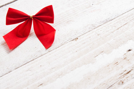 Decorative red ribbon and bow on a background of white painted rustic boards