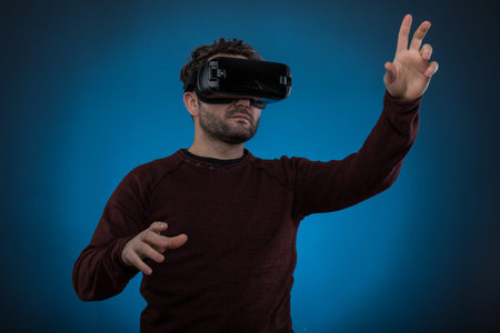 Handsome man wearing future technology VR glasses ,Studio shot, blue backgroun.