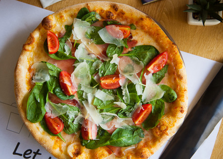 Pizza with salami and tomatoes on a restourant background, top viewの写真素材