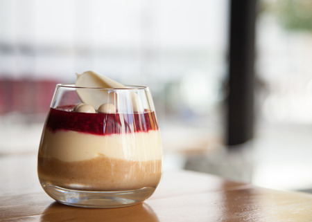 cheesecake with raspberries and decorated with white chocolade in glass on old wooden backgroundの写真素材