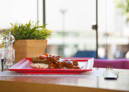 Sweet and Sour Chicken on Rice with vegetable served in a restourant on a red plateの写真素材