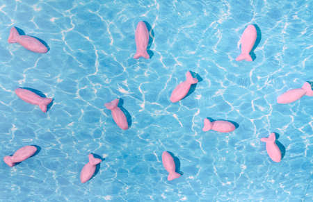 Cute pink fishes swimming in the sea or in the ocean. Surreal summer vibes fantasy concept. Pastel trend creative design.の写真素材