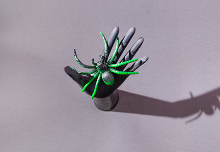A black hand holding a big black and green spider. Grey background. Halloween 2021 horror concept. Spooky retro creative design.の写真素材