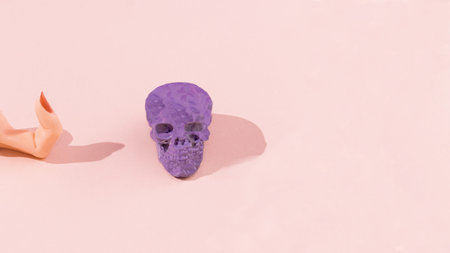A women's finger with red nail calling a lilac scull. Pastel pink background. Surreal Halloween creative concept. Scary love and attraction design.の写真素材