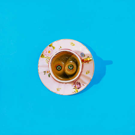 An old fashioned cup for coffee made of porcelain, with charming flowers on it. Two eye balls emerging from the coffee. Halloween scary invitation creative concept.の写真素材