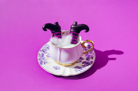 An old fashioned cup for coffee made of porcelain, with charming flowers on it. Two witch black boots emerging from spider web in the cup. Halloween scary invitation creative concept.の写真素材