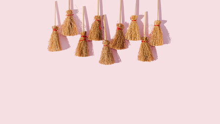 Nine brooms aligned on the top of a pastel pink background. Flat lay. Wallpaper or background or pattern for Halloween banner.の写真素材