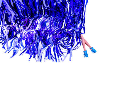 Women's legs wearing blue high heels shoes emerging from behind curtains made of shiny blue metalic tinsels. White background.の写真素材