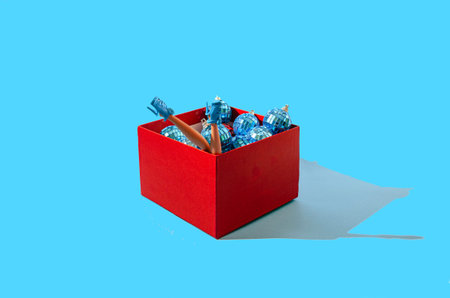 A red box full of shiny blue disco balls and two women's legs with blue shoes. Pastel blue...