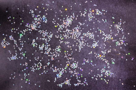 A background or backdrop or wallpaper in dark grey with shiny silver tinsels in the shape of stars. Design for advertisement, banner or card.の写真素材