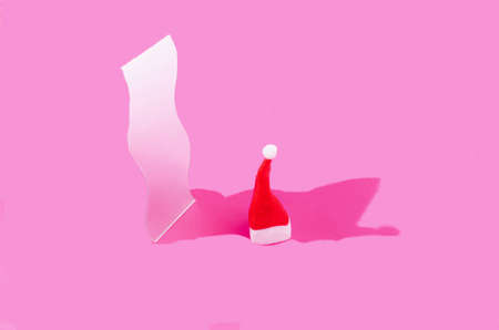 Santa Claus red hat in front of a mirror on magenta pink background. Surreal Christmas web banner artistic design. Creative concept for New Year's eve partyの写真素材