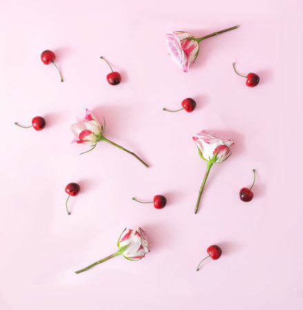 A pattern made of white and magenta roses and cherries on pastel pink background. Elegant creative concept for spring summer background. Flat lay.の写真素材