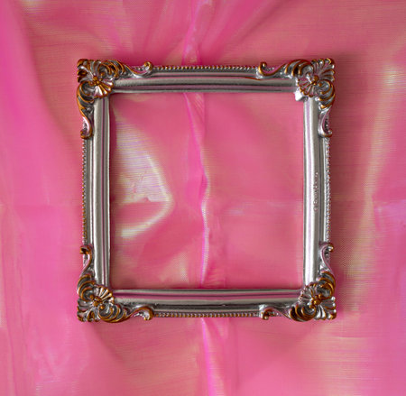 A retro silver frame on shiny pink fabric. Background for invitation, card or announcement. Design for advertisement. Copy spaceの写真素材