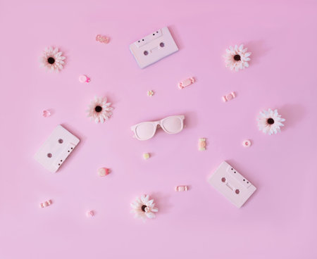 A wallpaper made of pink audio tapes, flowers, candies and sunglasses on pastel pink background. Retro design for summer party invitation or banner.の写真素材