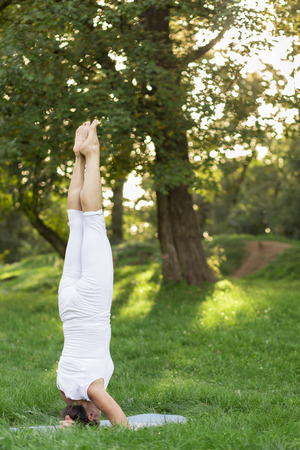 Middle aged woman doing yoga early in the morning in a parkの写真素材