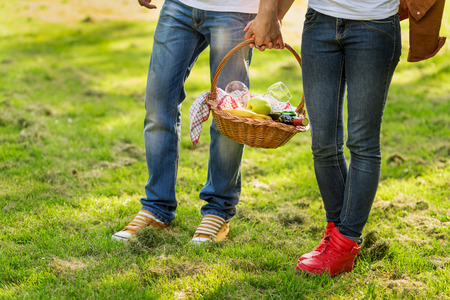 Couple in love walking through nature, holding hands and carrying a picnic basketの写真素材