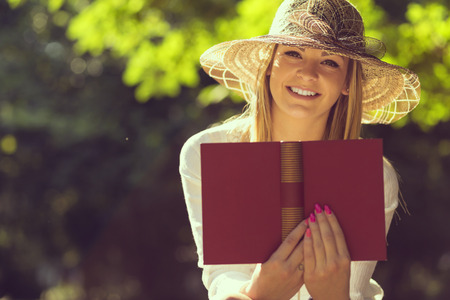 Young woman reading a book on a sunny summer day in the parkの写真素材