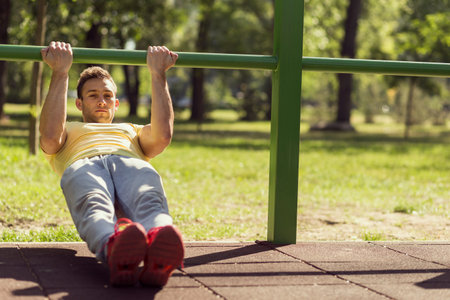 Muscular built young athlete working out in an outdoor gym