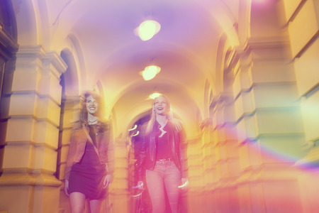 Two girls walking down the city streets, ready for a night out with friendsの写真素材