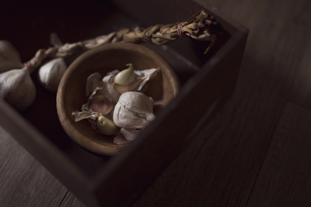 Top view of a garlic bulb and cloves placed in a wooden bowl and crate. Selective focusの写真素材